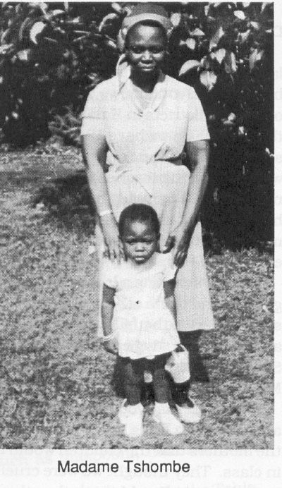 Madame Tshombe standing with a small child in front of leafy foliage, Belgian Congo